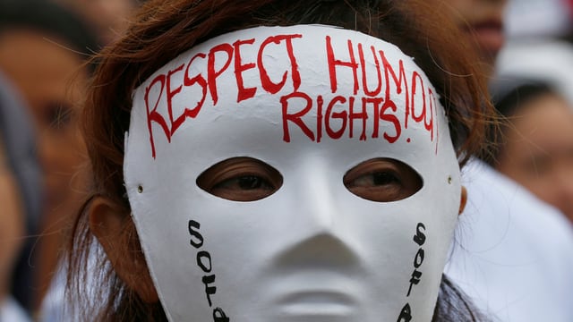 Eine Frau trägt eine Maske mit der Aufschrift Respect Human Rights. Eine Frau trägt eine Maske mit der Aufschrift Respect Human Rights.