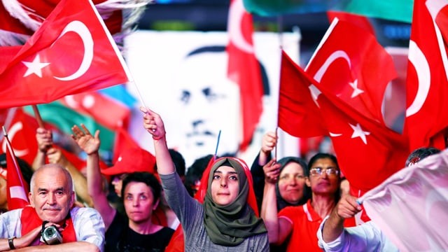 Menschenmenge schwenkt türkische Fahnen.