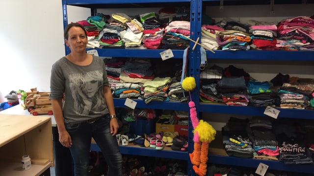 Eine Frau steht vor Regalen mit Kleidern und Schuhen. Eine Frau steht vor Regalen mit Kleidern und Schuhen.