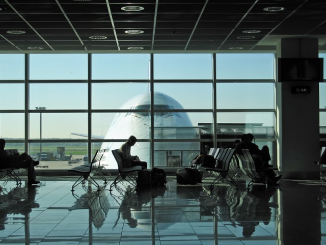 Vor einem Gate in einem Flughafen warten Reisende aufs Boarding. Vor einem Gate in einem Flughafen warten Reisende aufs Boarding.