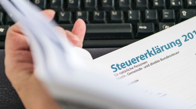 Ein Mann hält die Steuererklärung in der Hand. Ein Mann hält die Steuererklärung in der Hand.