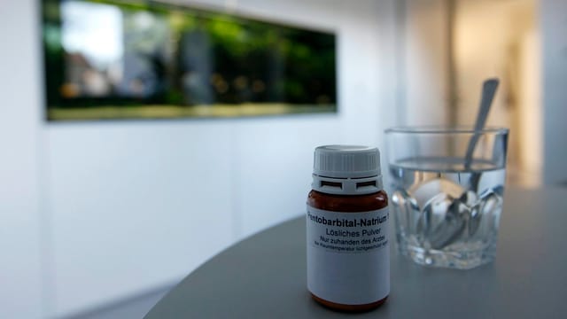 Auf einem Tisch steht ein Pulver und ein Glas Wasser. Auf einem Tisch steht ein Pulver und ein Glas Wasser.