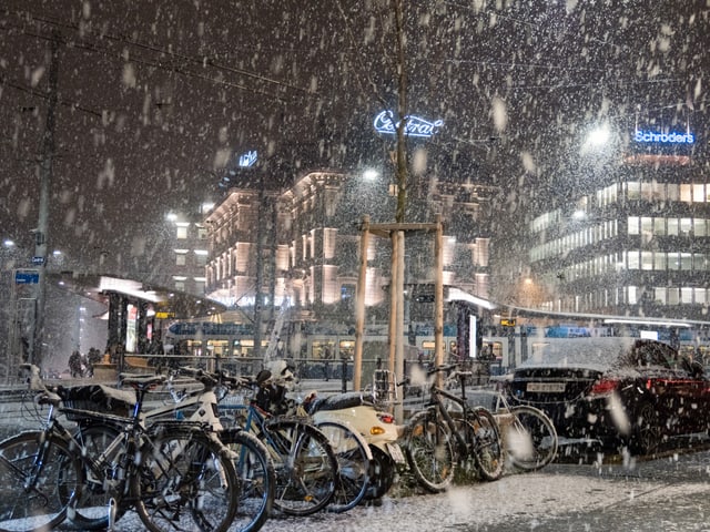 Es schneit auf Fahrräder im Dunkeln.