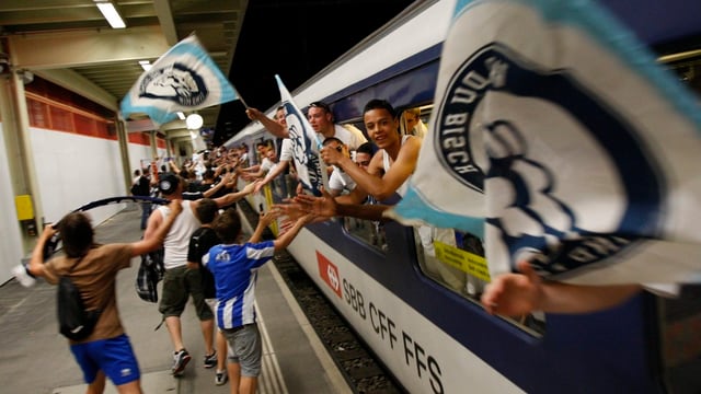 Feiernde Sportfans mit Fahnen in einem Zug Feiernde Sportfans mit Fahnen in einem Zug
