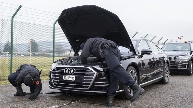 Ein Polizist beugt sich über eine geöffnete Motorhaube, eine zweiter hält mit einer Stange eine Kamera unter das Auto Ein Polizist beugt sich über eine geöffnete Motorhaube, eine zweiter hält mit einer Stange eine Kamera unter das Auto