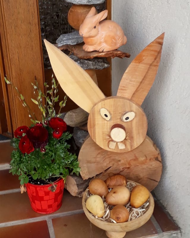 Osterdekoration mit Holz- und Keramikhase und Holzeiern.