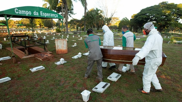 Men in protective clothing carry a coffin Men in protective clothing carry a coffin