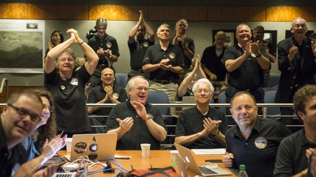 Männer in schwarzen T-Shirts mit Nasa-Logo klatschen im Sitzen und im Stehen. Männer in schwarzen T-Shirts mit Nasa-Logo klatschen im Sitzen und im Stehen.