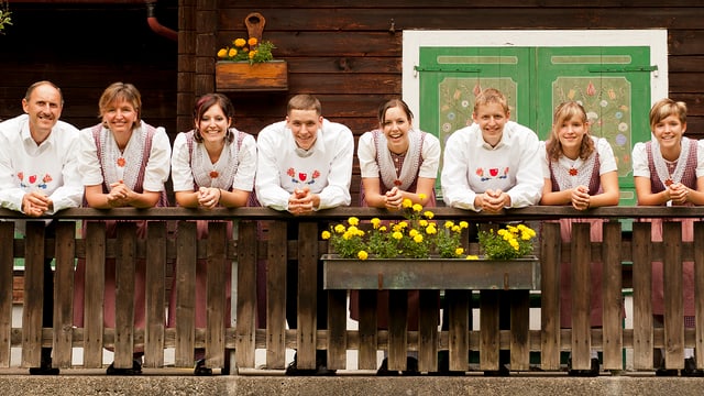 Familie lächelt vom Balkon eines alten Emmentaler Bauernhauses herab. Familie lächelt vom Balkon eines alten Emmentaler Bauernhauses herab.