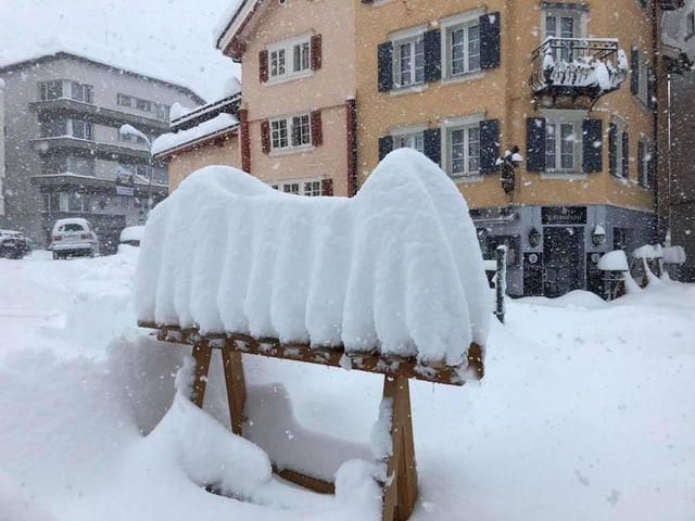 Schneemassen türmen sich auf einem Skiständer aus Holz.