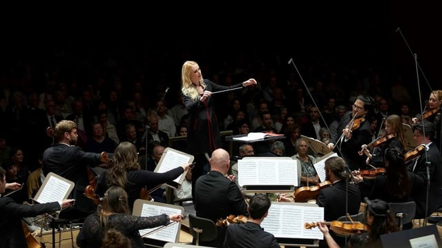 Eine blonde Frau dirigiert ein Orchester Eine blonde Frau dirigiert ein Orchester