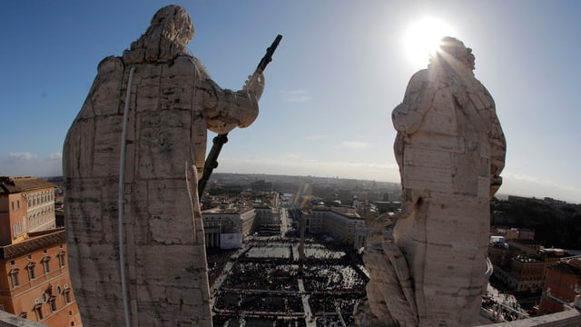 Blick auf den Petersplatz: Hinter zwei grossen Steinstatuen ist die Masse zu sehen, die sich zur Inauguration des neuen Papstes Franziskus eingefunden hat.