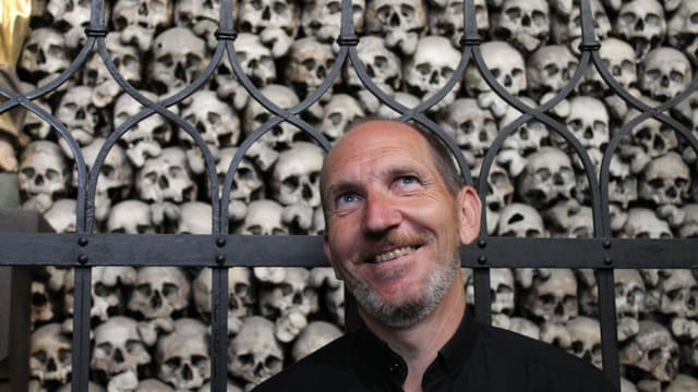 Mann vor Totenschädeln Mann vor Totenschädeln