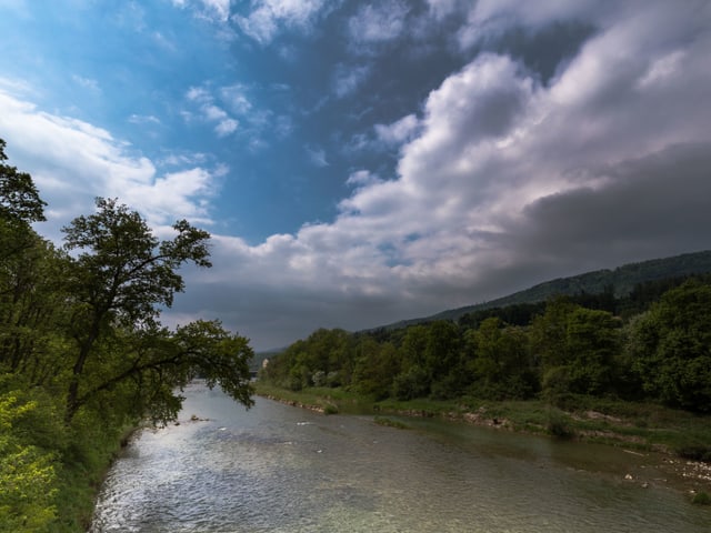 Ein Fluss gesäumt von Grün, ein Stück blauer Himmel.