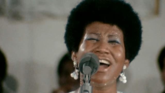 Eine afroamerikanische Frau singt ins Mikrofon.