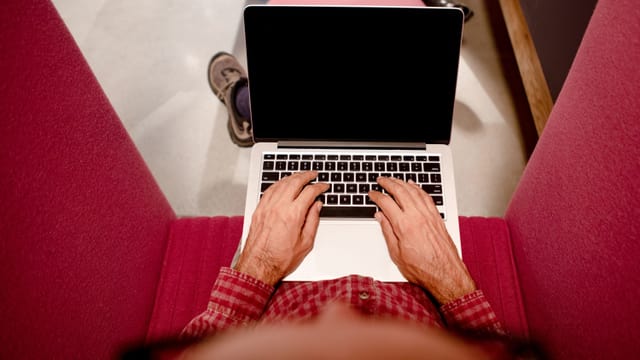 Ein Mann mit einem Laptop auf den Knien von oben fotografiert. Ein Mann mit einem Laptop auf den Knien von oben fotografiert.