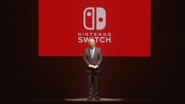 Vor einem grossen roten Switch-Logo. Vor einem grossen roten Switch-Logo.