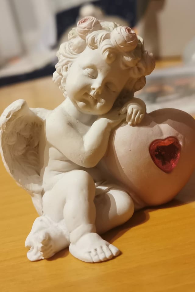 Keramikengel stützt sich auf Herz.