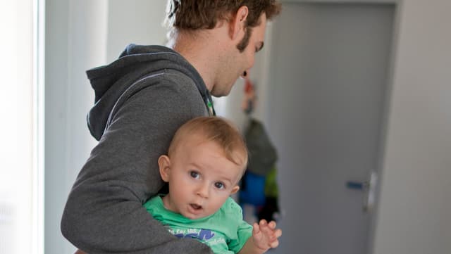 Ein Vater hält sein Kind auf dem Arm. Ein Vater hält sein Kind auf dem Arm.