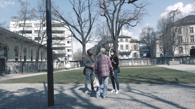 Drei Menschen stehen im Stadtpark Chur Drei Menschen stehen im Stadtpark Chur