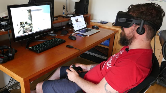 SRF Digitalredaktor Guido Berger sitzt im Bürostuhl mit angezogener VR-Brille und spielt eine Raumschiff-Simulation.