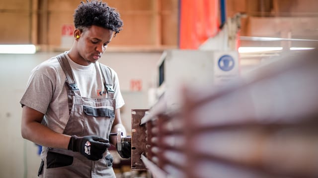 Ein junger Flüchtling arbeitet an einer Maschine. Ein junger Flüchtling arbeitet an einer Maschine.