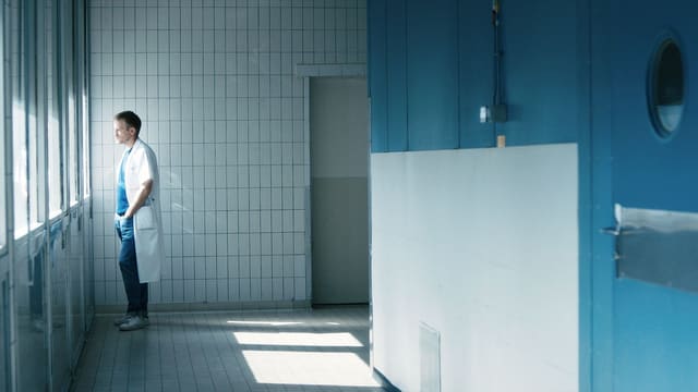 Ein Arzt in der Klinik: er schaut nachdenklich aus dem Fenster. Ein Arzt in der Klinik: er schaut nachdenklich aus dem Fenster.