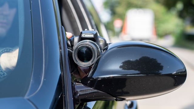 Sozialdetektiv reckt Kamera aus dem Auto Sozialdetektiv reckt Kamera aus dem Auto