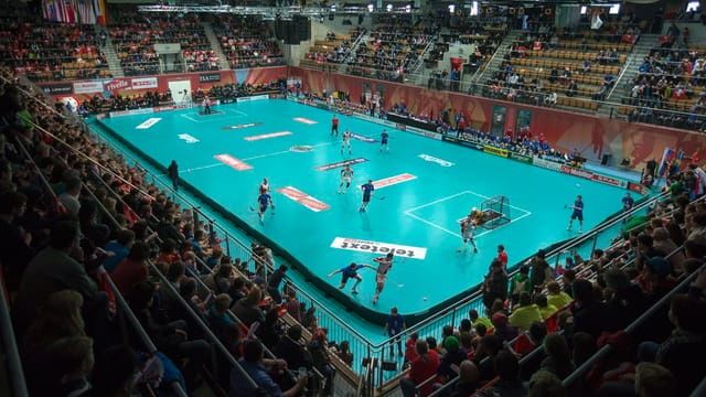 Sporthalle mit mehreren Unihockeyspielern Sporthalle mit mehreren Unihockeyspielern