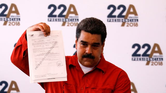 Nicolas Maduro, der ein Dokument in der Hand hält. Nicolas Maduro, der ein Dokument in der Hand hält.