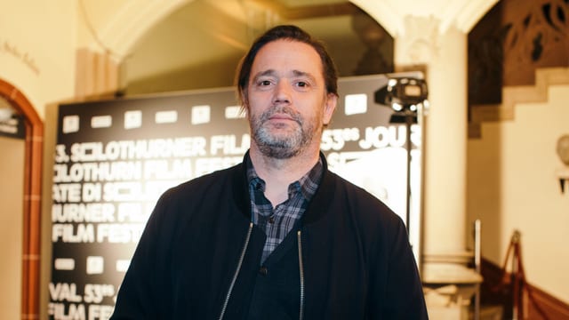 Ein Mann mit grauem Bart vor einer Werbetafel der Solothurner Filmtage. Ein Mann mit grauem Bart vor einer Werbetafel der Solothurner Filmtage.
