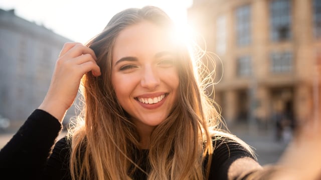 Eine hübsche junge Frau lächelt in die Kamera, die Sonne umspielt ihr Gesicht. Eine hübsche junge Frau lächelt in die Kamera, die Sonne umspielt ihr Gesicht.