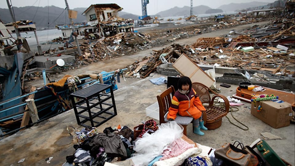 Ein Mädchen mit dem wenigen Hab und Gut, das der Tsunami seiner Familie gelassen hat.