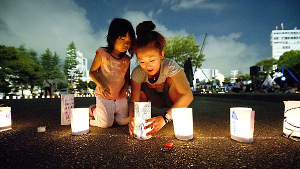 Eine Japanerin zündet mit ihrer Tochter eine Kerze an, zum Gedenken an die Opfer in Japan im März 2011.