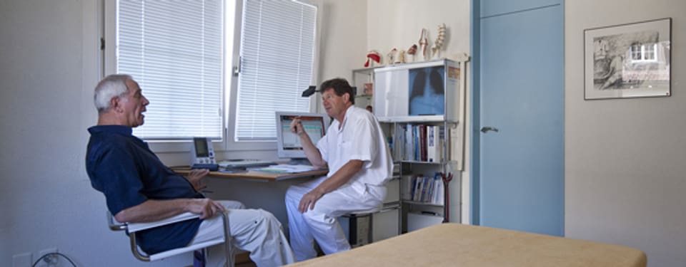 Allgemeinpraktiker Peter Zaech berät einen Patienten mit Rückenschmerzen.