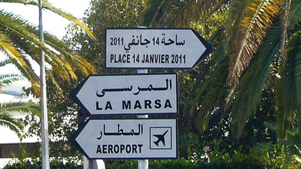 Wegweiser zum «Place 14 Janvier 2011», der auf dem Stadtplan allerdings immer nohc «Place de 7 Novembre 1987» heisst und auf die Zeit vor der Revolution verweist.