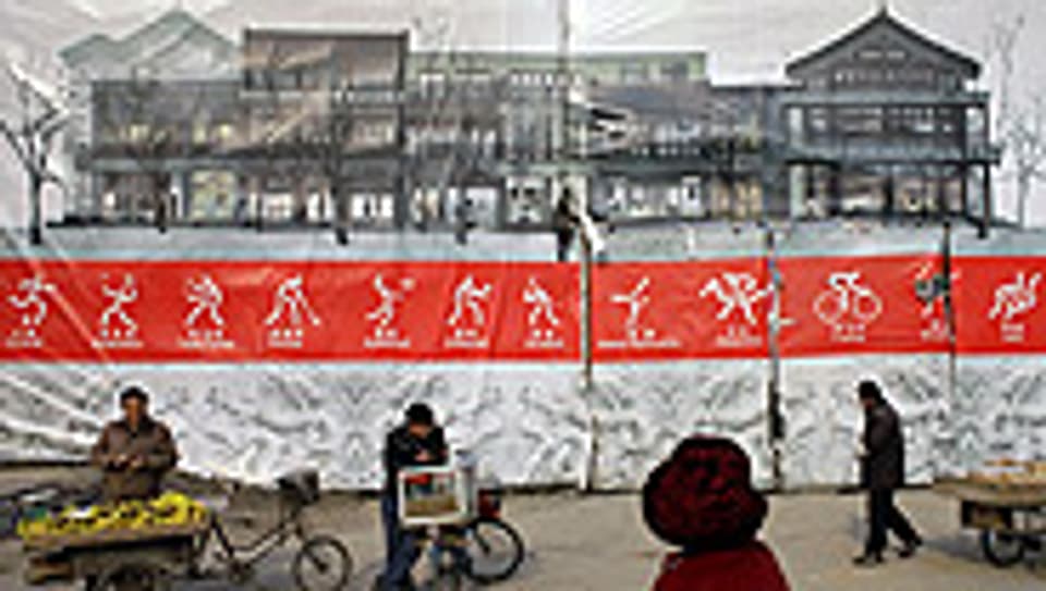Verkäufer stehen vor einem Werbeplakat für die Olympiade in Peking.