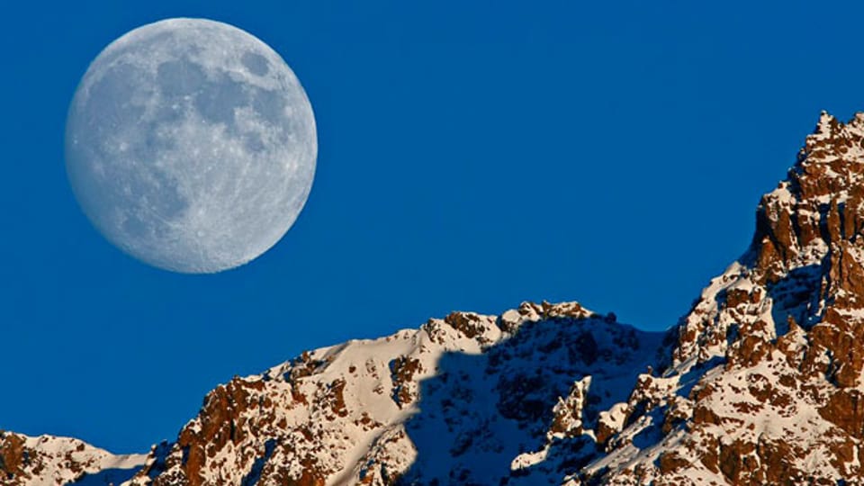 Ein fast voller Mond steigt über der Tijerflue in Arosa auf.