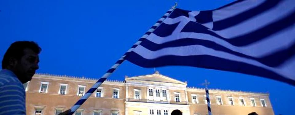 Ein Demonstrant schwenkt die griechische Flagge vor dem Parlamentsgebäude in Athen.