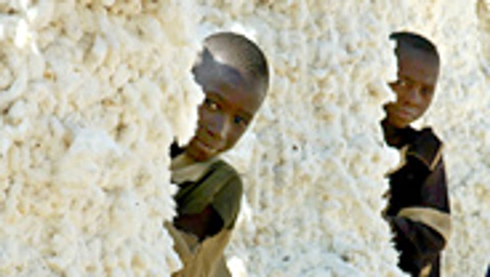 Kinder verstecken sich hinter Baumwollballen in Bukina Faso.