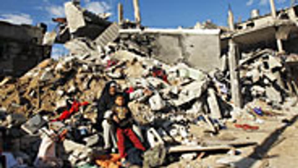 Palästinenser im Gazastreifen sitzen auf den Trümmern ihres Hauses.