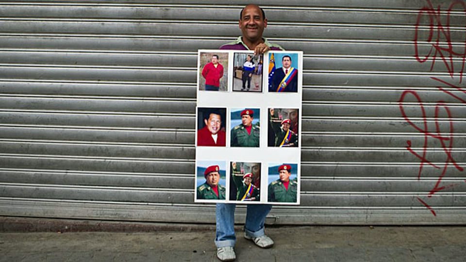 Ein Mann präsentiert in Venezuelas Hauptstadt Caracas ein Plakat mit Bildern von Hugo Chavez.