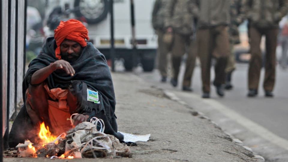 Ein Sadhu wärmt sich am Feuer im indischen Jammu.