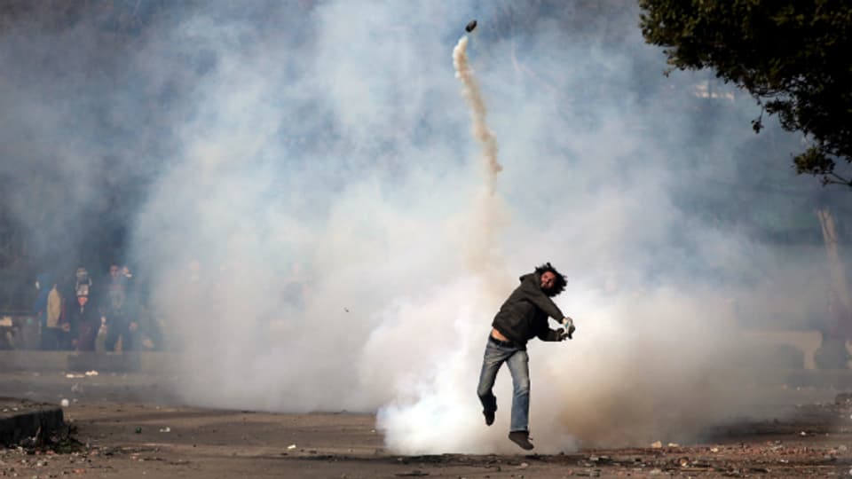 Ein Demonstrant wirft eine Tränengas-Granate bei Protesten in Kairo.
