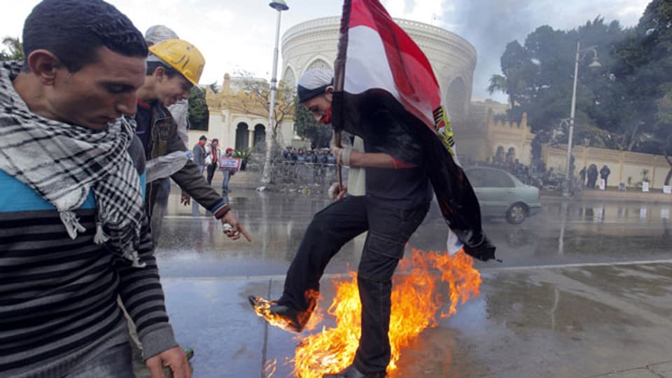 Ein protestierender Ägypter versucht vor Flammen zu fliehen, nachdem er vor dem Präsidentenpalast in Kairo eine Anti-Mursi-Flagge angezündet hatte.