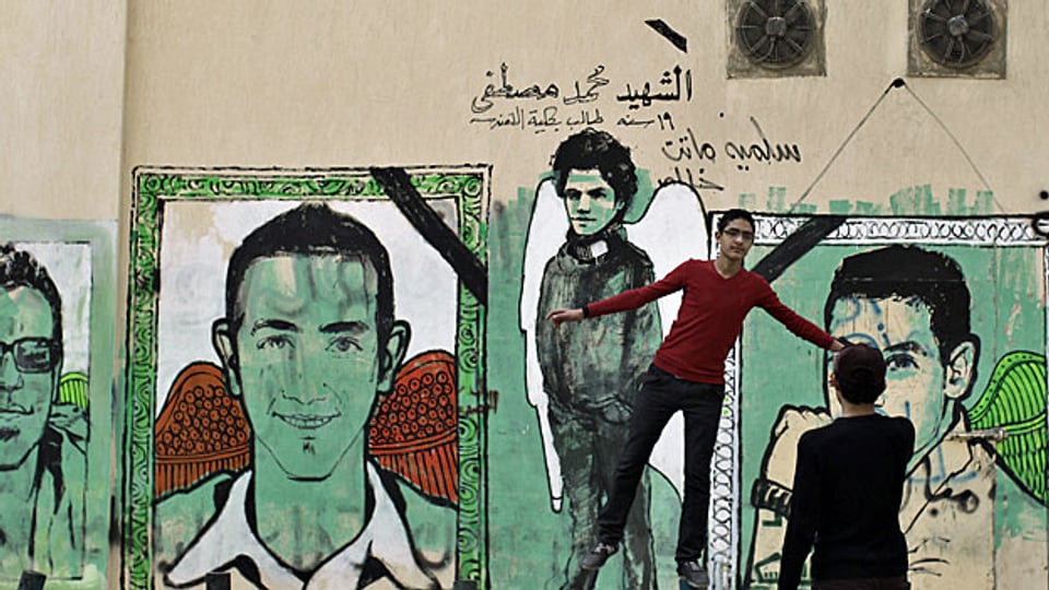 Jugendliche vor Wandbildern in einer Strasse von Kairo.