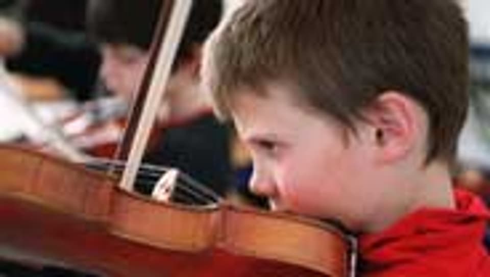 Ein Junge probiert, wie es ist auf einer Geige zu spielen.