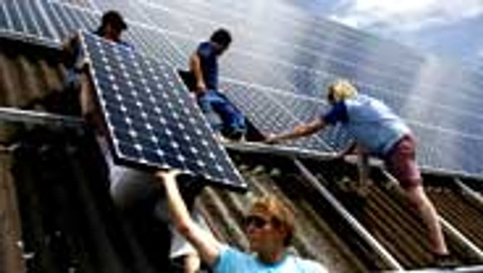 Jugendliche montieren Solarzellen auf einem Scheunendach Ruswil.