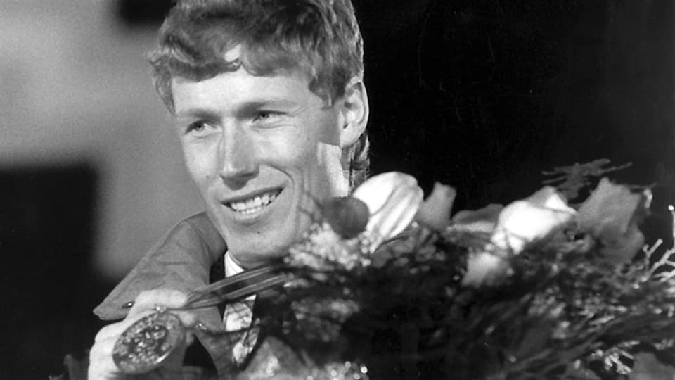 In einer Zeit von 1:59,63 Minuten gewinnt Pirmin Zurbriggen am 15. Februar 1988 bei den XV. Olympischen Winterspielen in Calgary die Abfahrt. Bei der Siegerehrung präsentiert der Walliser stolz seine Goldmedaille.