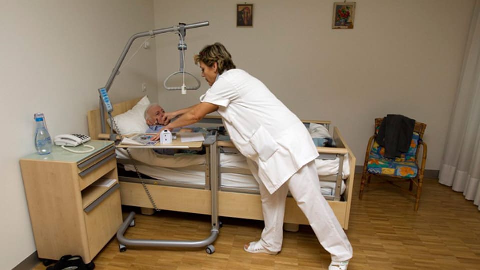 Eine Pflegerin pflegt eine Frau in ihrem Bett.